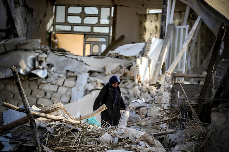 A woman stands in the rubble after the earthquake